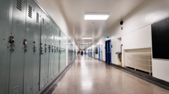 A mostly empty school hallway, with lockers on the left and classrooms on the right.