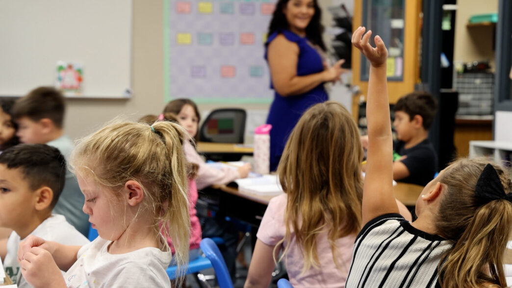 Litchfield Elementary School student raises hand in class while teacher looks on. (Katie Wilcox/The Beam)