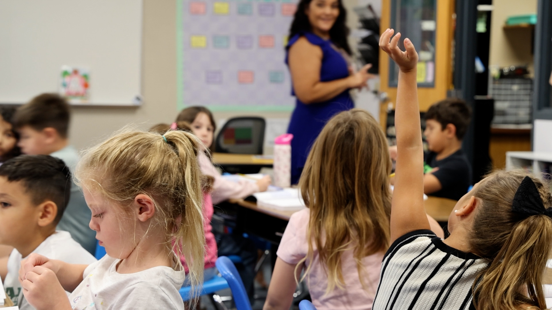 Litchfield Elementary School student raises hand in class while teacher looks on. (Katie Wilcox/The Beam)